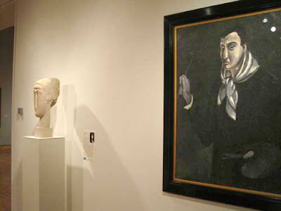 Stylized white marble head sculpture next to a monochrome black and gray painting of a man, head dominant