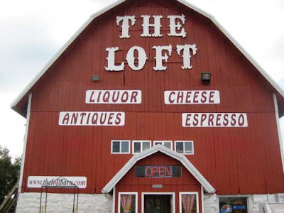 Red barn with large sign reading The Loft then smaller words, LIQUOR CHEESE ESPRESSO ANTIQUES