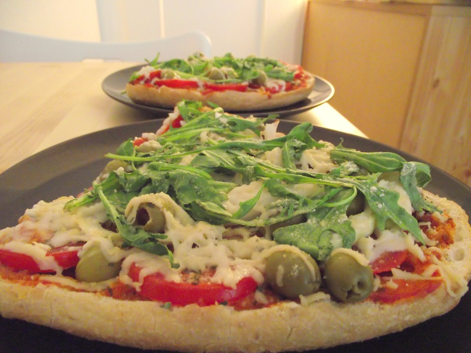 vegane Fladenbrotpizza mit Rucola und Oliven