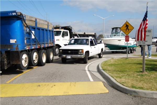 Pedestrian crossing, dump trucks & boats on trailers.