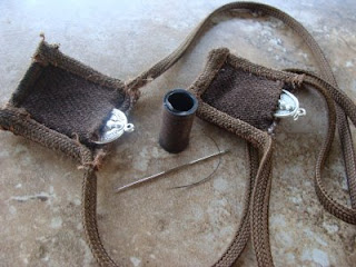 Brown square pockets tethered together and a brown thread spool with needle