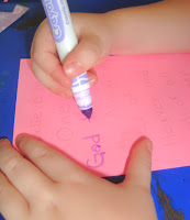Pink construction paper being written on with purple marker