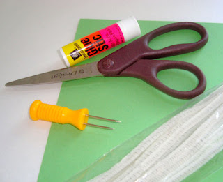 Pipecleaner, corn cob holder, glue stick, green construction paper, and scissors