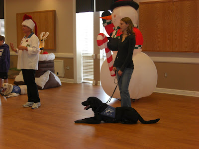 Picture of Rudy in coat in a down-stay beside me. Our group is doing obedience