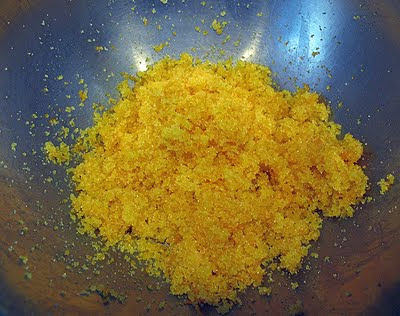 A close up photo of orange zest and granulated sugar in a mixing bowl.