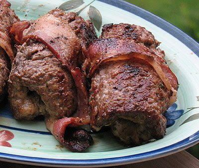 A close up photo of grilled cube steak rollups on a decorative green plate.