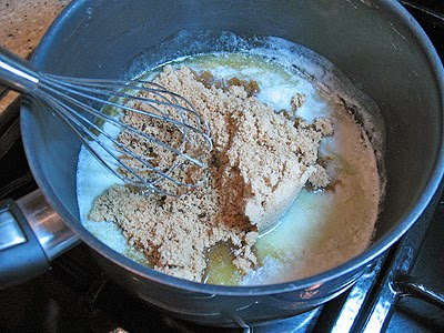 A close up photo of brown sugar being whisked into melted butter in a saucepan.