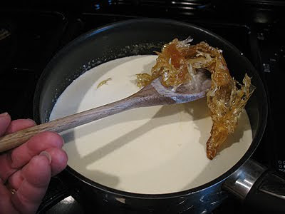 A photo of the solidified caramel being lifted out of the cream with a wooden spoon.