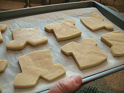 A close up photo of football jersey shaped cookies on a pan with parchment paper.