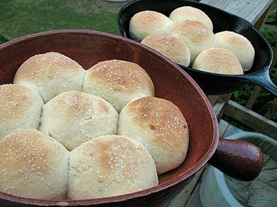 A close up photo of homemade dinner rolls resting in two cast iron skillets.