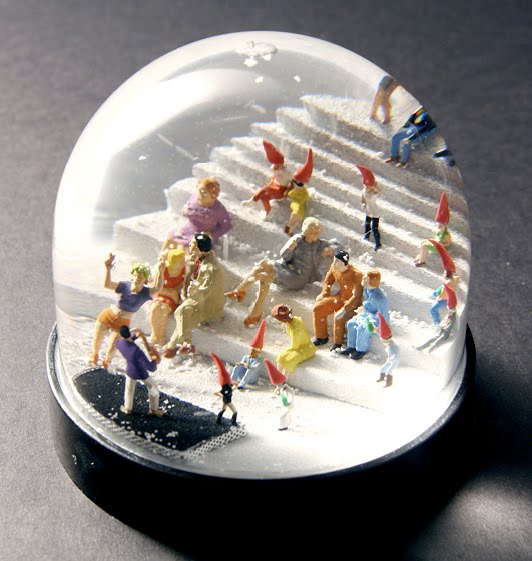 Man & Christmas Elf Explored In 14 Snowglobes By Various Architects.