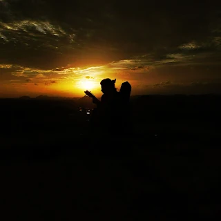 A tourist playing her guitar while witnessing the sunset at Hampi