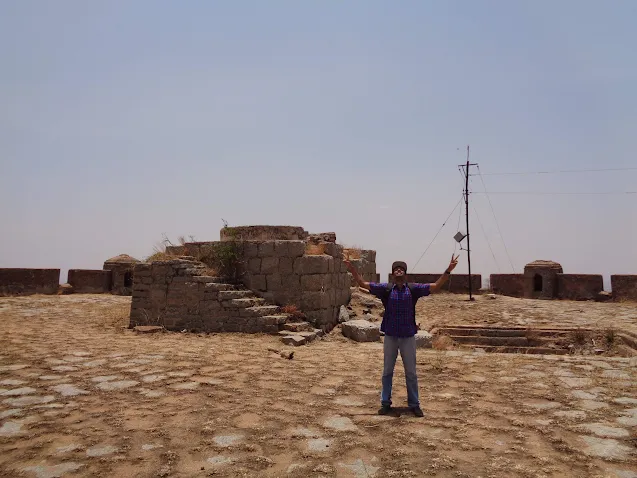 Hiker at the summit of pavagada showing the victory sign