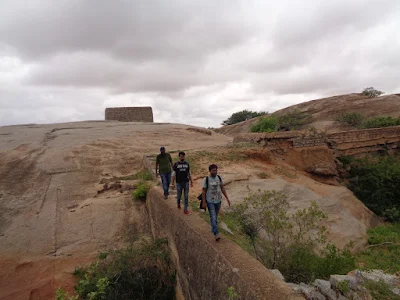 Hikers in the balancing act across a wall which separates two water holding cells.