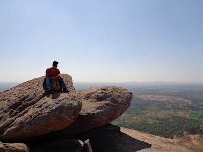 Sippy sitting atop a boulder at the summit of Kunti betta trek enjoying some choclates